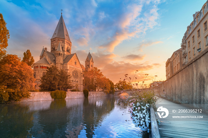 A colourful city view of an ancient Neuf Church on the bank of the Moselle river in Metz in France during the sunrise. Tourist attractions and city life concept