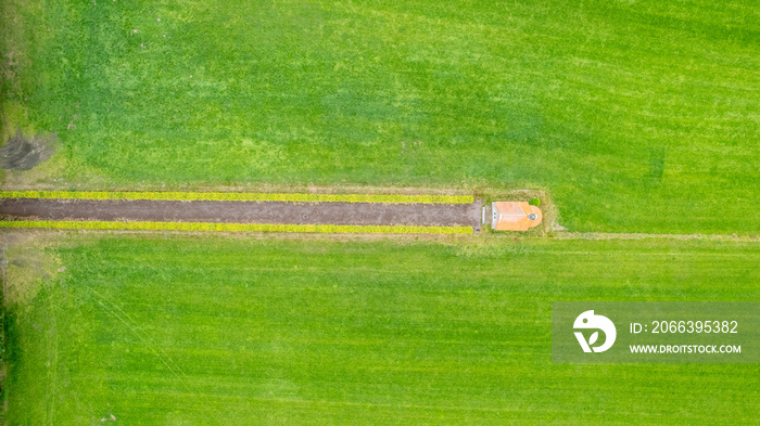 garden detail in aerial view with sand path going between two hedges towards a little building, a shed or chapel, in the middle. High quality photo