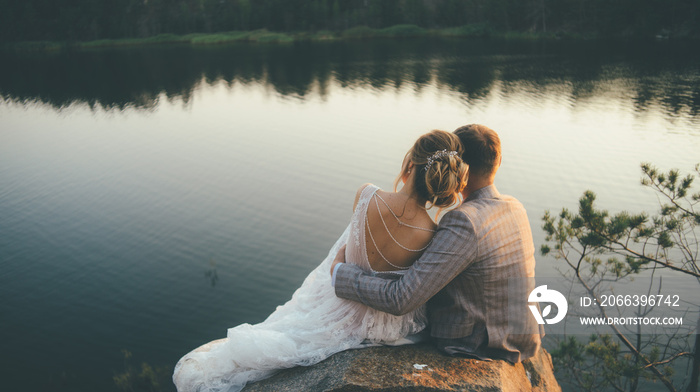 beautiful wedding couple sitting hugging looking to the sunset