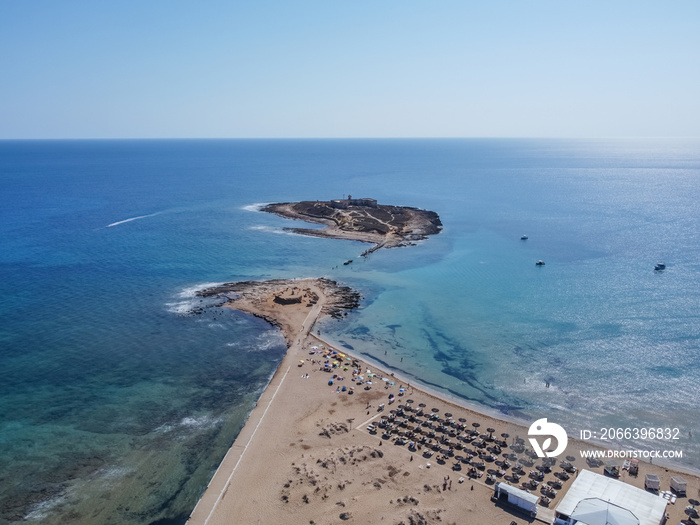 Aerial drone view of island and beach of Isola delle Correnti. Lighthouse surrounded by clear turquoise sea water in Portopalo di capo Passero, Sicily