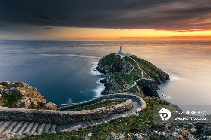 Lighthouse on coastal island with horizon and beautiful sunset at South Stack in Holyhead, North Wales. South Stack lighthouse at sunset overlooking the Irish Sea Isle of Anglesey