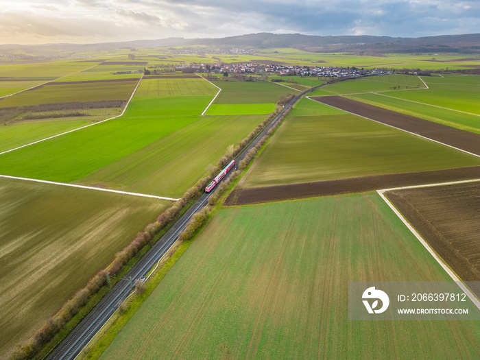 aerial view of train driving through the fields in the countryside