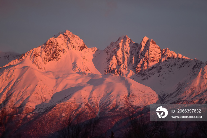 Spring alpenglow tints a snow-covered Alaska mountain at sunset.