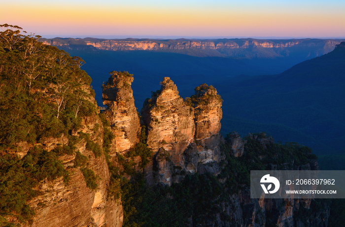 Orange glow of sunset on the peaks of the Three Sisters landmark in the Blue Mountains of Australia