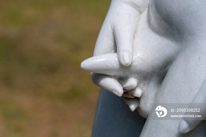 Detail marble statue of naked pissing boy in tropical garden in Danang, Vietnam, closeup