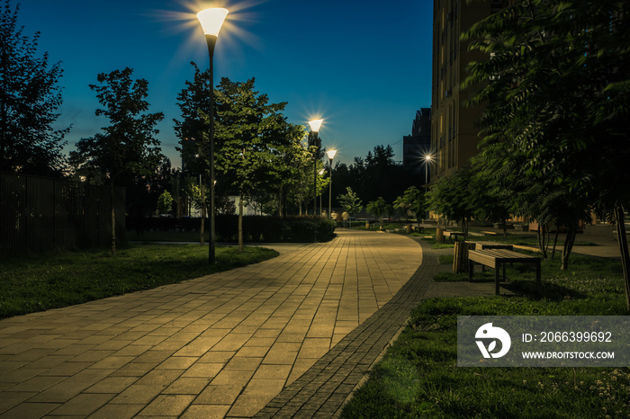 Night park paths and colored houses at summer night. Night paths, benches and lanterns in a beautiful residential complex. Night summer park with lanterns and benches. Kyiv. Ukraine