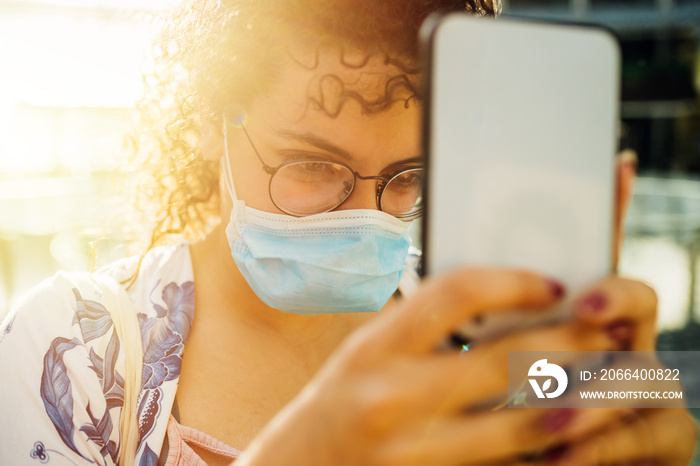 Young woman wearing medical mask taking selfie on street