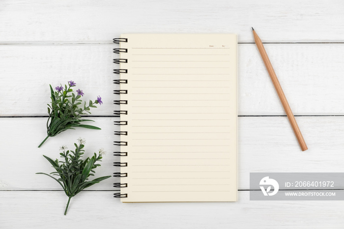 Top view of an open notebook with pencil on white wooden desk