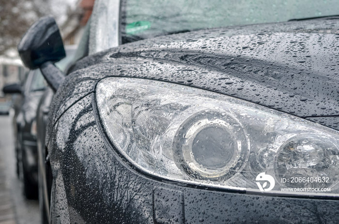 close up of a car headlight with drops of rain