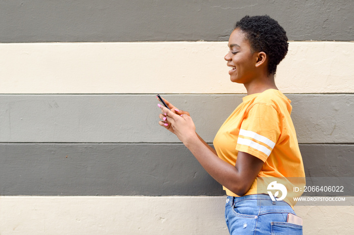 Black girl smiling and using her smart phone outdoors.