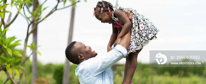 happy african american father playing with little daughter in green park.