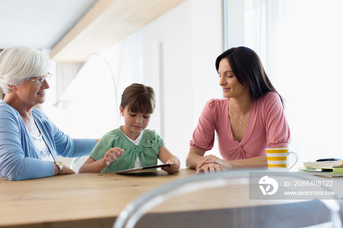 Multi-generation family using digital tablet at dining table