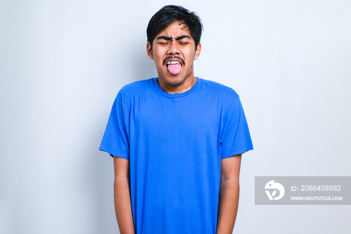 Boy wearing casual shirt sticking tongue out happy with funny expression. Emotion concept.