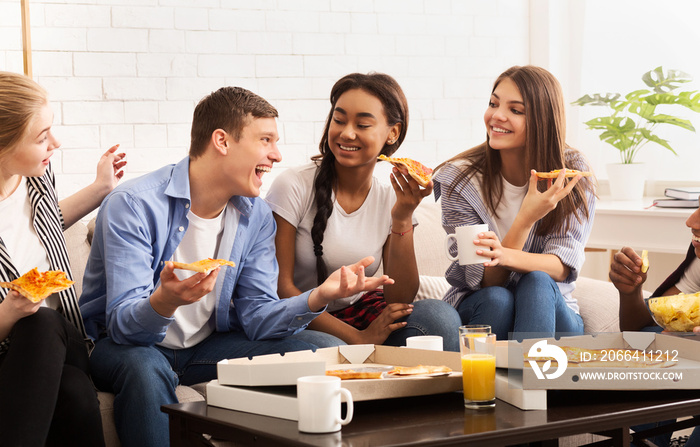 Happy teen roommates eating pizza and chatting at home