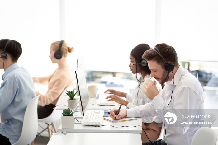 Multinational team of tech support operators at work at modern call centre office