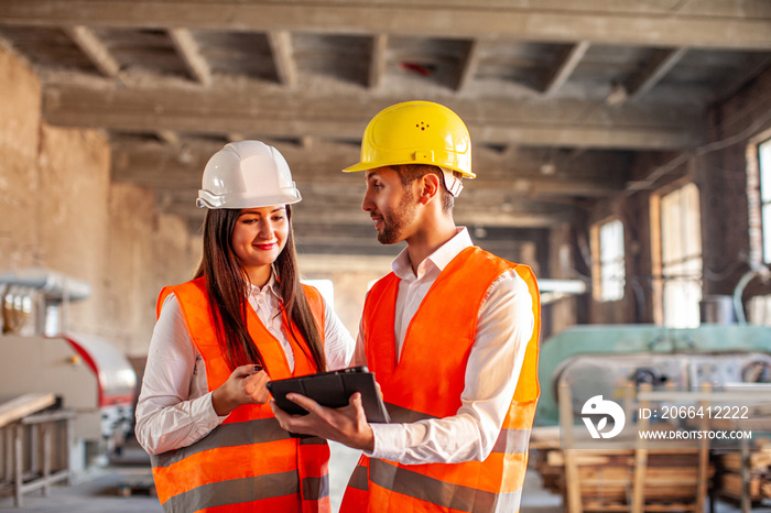 Smiling workers doing work using tablet at factory