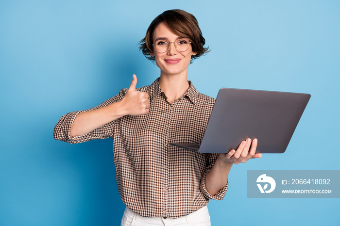 Portrait of positive nice girl hold laptop show thumb up wear checkered isolated on blue color backg