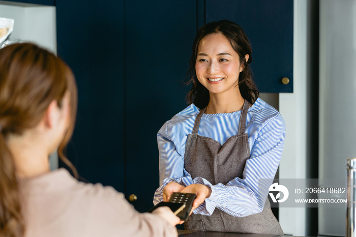 カフェでスマホ決済をする女性（飲食店・テイクアウト）