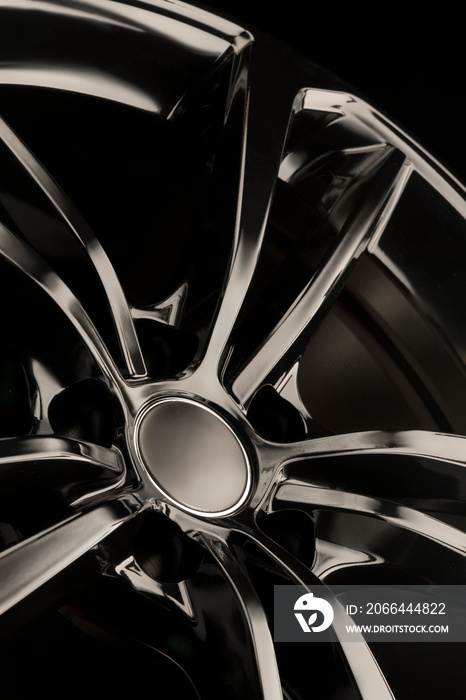 Black Gloss alloy wheel on a dark background. Stylish and expensive. Close-up of spoke elements, ver