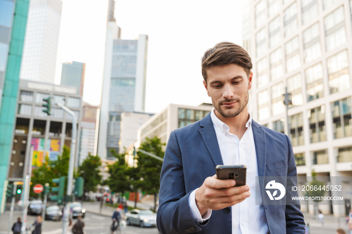 Handsome young business man standing near business center using mobile phone.