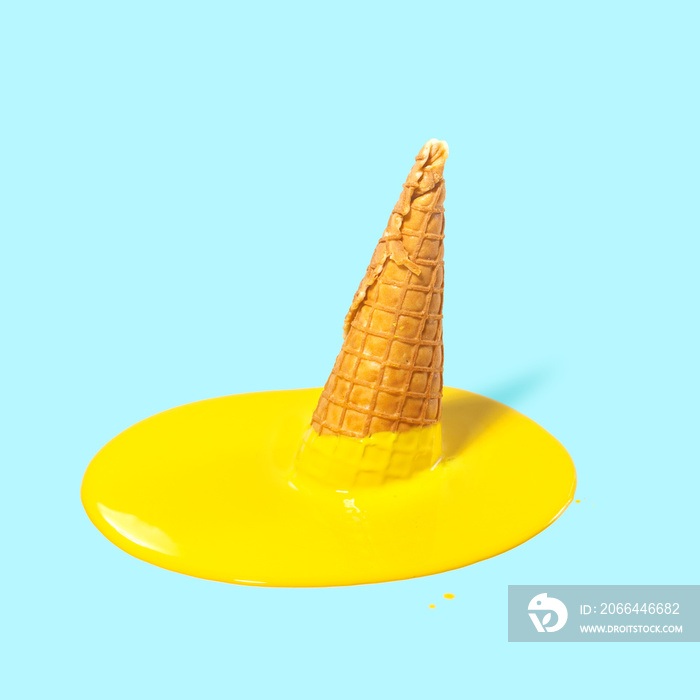 在淡蓝色背景下的华夫饼角中融化的黄色水果冰淇淋。夏日心情。创意创意