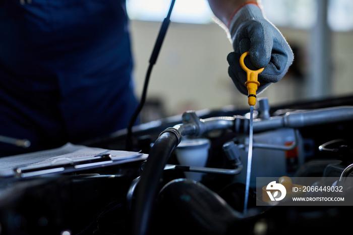 Close-up of a auto repairman checking car oil in a workshop.