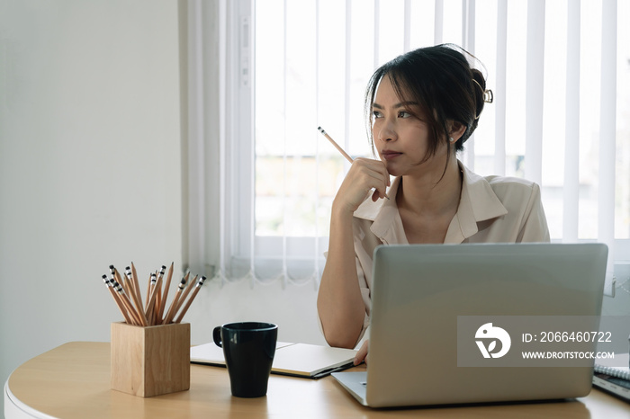 Portrait of business asian woman thinking and working with laptop computer in office