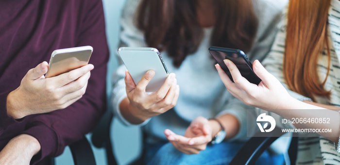 Group of young people using and looking at mobile phone while sitting together