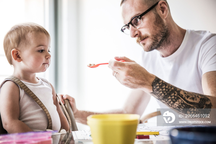 Father feeding his daughter at home