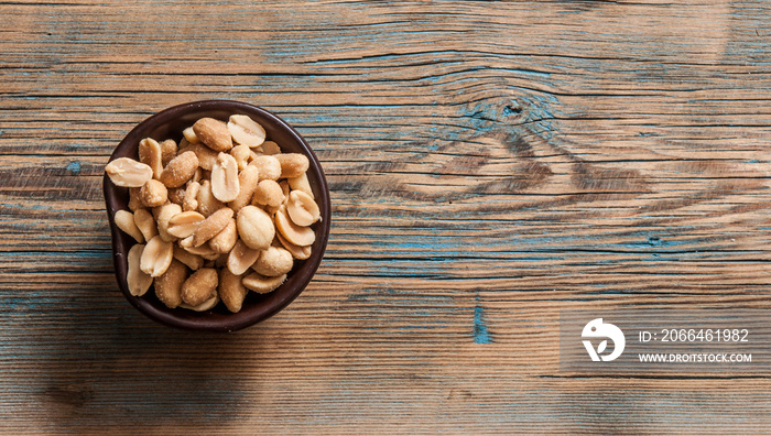 Roasted, salted peanuts are placed on a wooden background