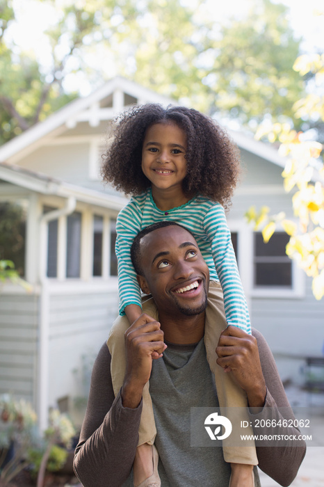 Portrait happy father carrying daughter on shoulders