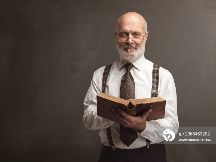 Academic professor smiling and reading a book