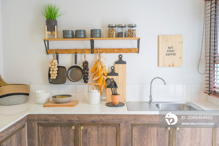 Arrangement of dry food products, spices and ceramics kitchen equipment hanging on country shelves i