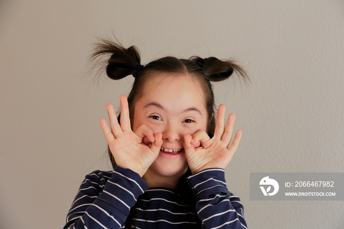 Cute smiling down syndrome girl on the grey background