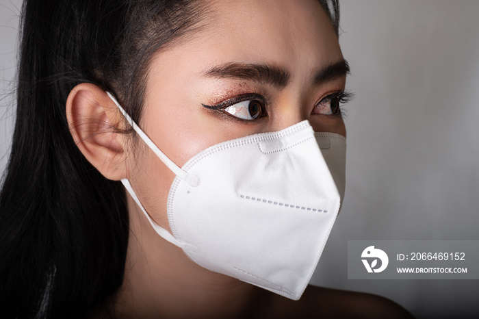 一名亚洲妇女戴上N95口罩以抵御空气传播的呼吸道疾病的特写