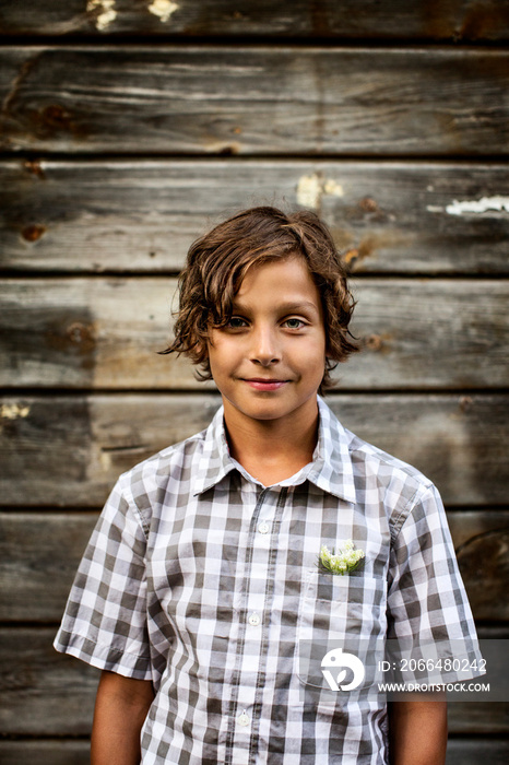 Portrait of boy standing against wooden wall