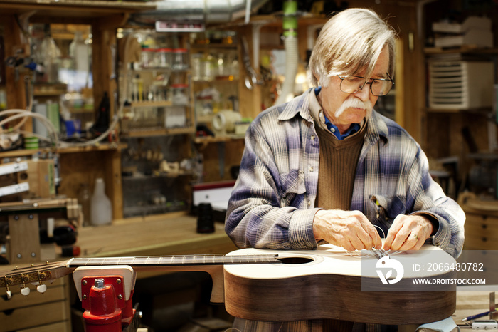 Man adjusting guitar strings in workshop