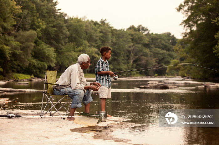 Boy and grandfather fishing in river