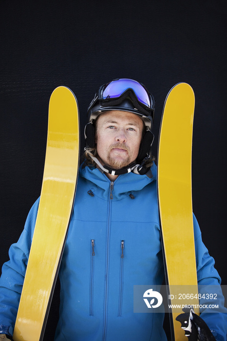 拿着黄色滑雪板站着的滑雪者肖像