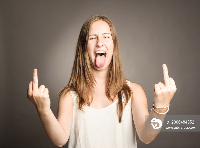 young woman showing middle fingers on a gray background