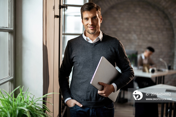 Portrait of confident businessman with laptop in the office.