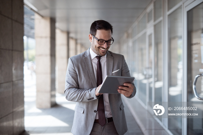 Businessman using tablet to check e-mail while standing in front of business center.