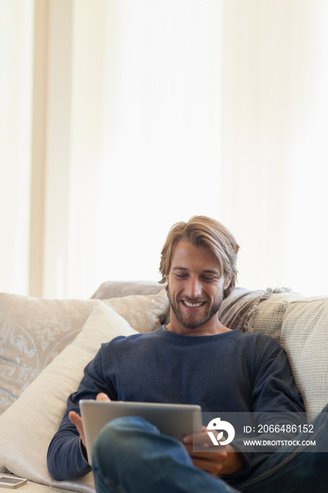 Smiling young man using digital tablet on sofa