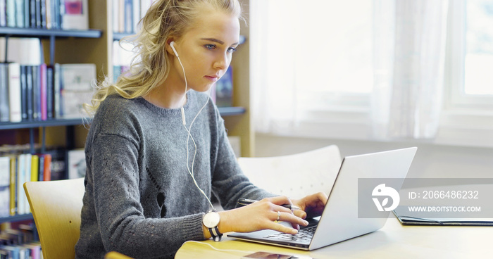 Hardworking female student working on laptop in the library