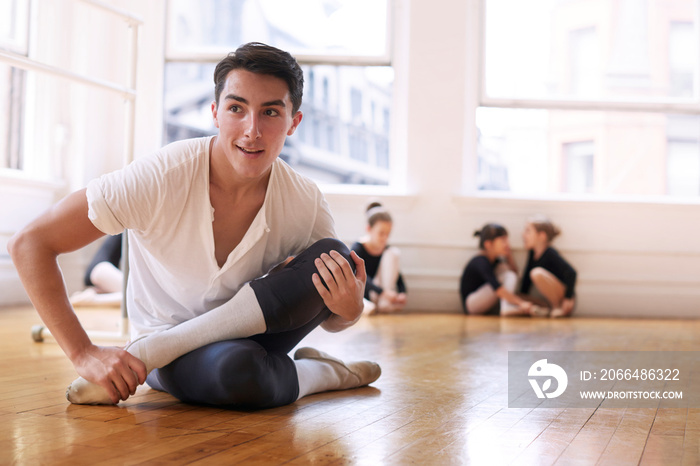 Ballet teacher stretching during lesson in studio