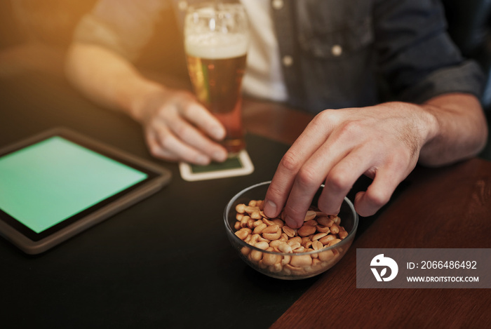 man with tablet pc, beer and peanuts at bar or pub