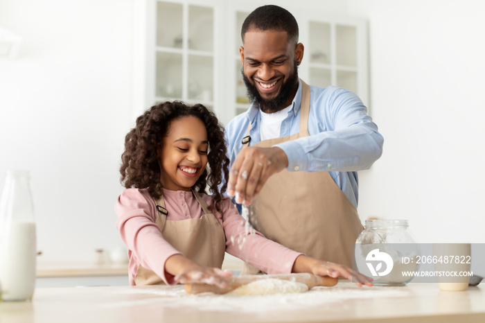 Happy black guy and his child daughter kneading dough