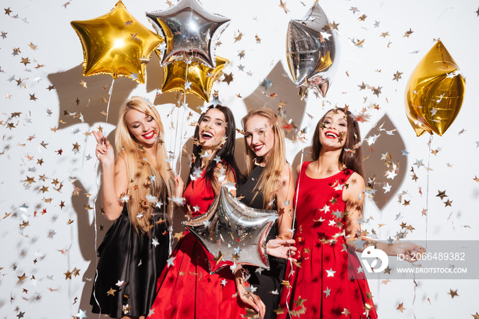 Four joyful young women with balloons and confetti having party