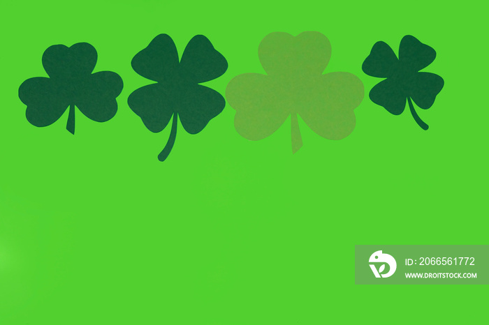 Paper shamrocks on bright green background with copy space