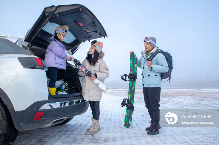 准备去滑雪的三口之家从汽车后备箱里拿滑雪板